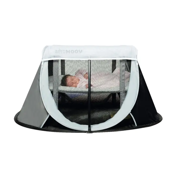 Кровать-манеж AeroMoov Instant Travel Cot с надетой москитной сеткой, внутри спит малыш