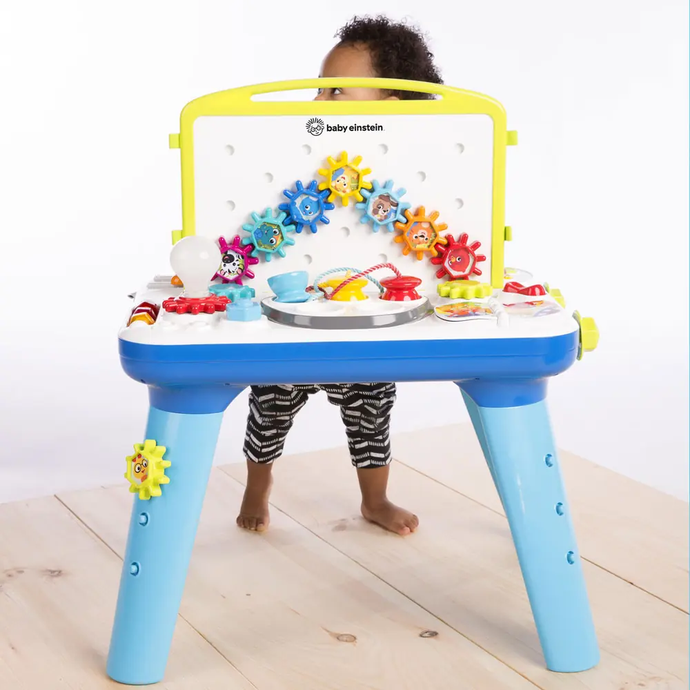 Дитина стоїть біля ігрового центру Baby Einstein Curiosity Table