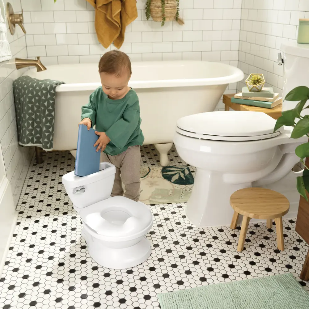 Ребенок достает предмет из отсека на месте бачка горшка-унитаза Ingenuity My Size Potty Pro