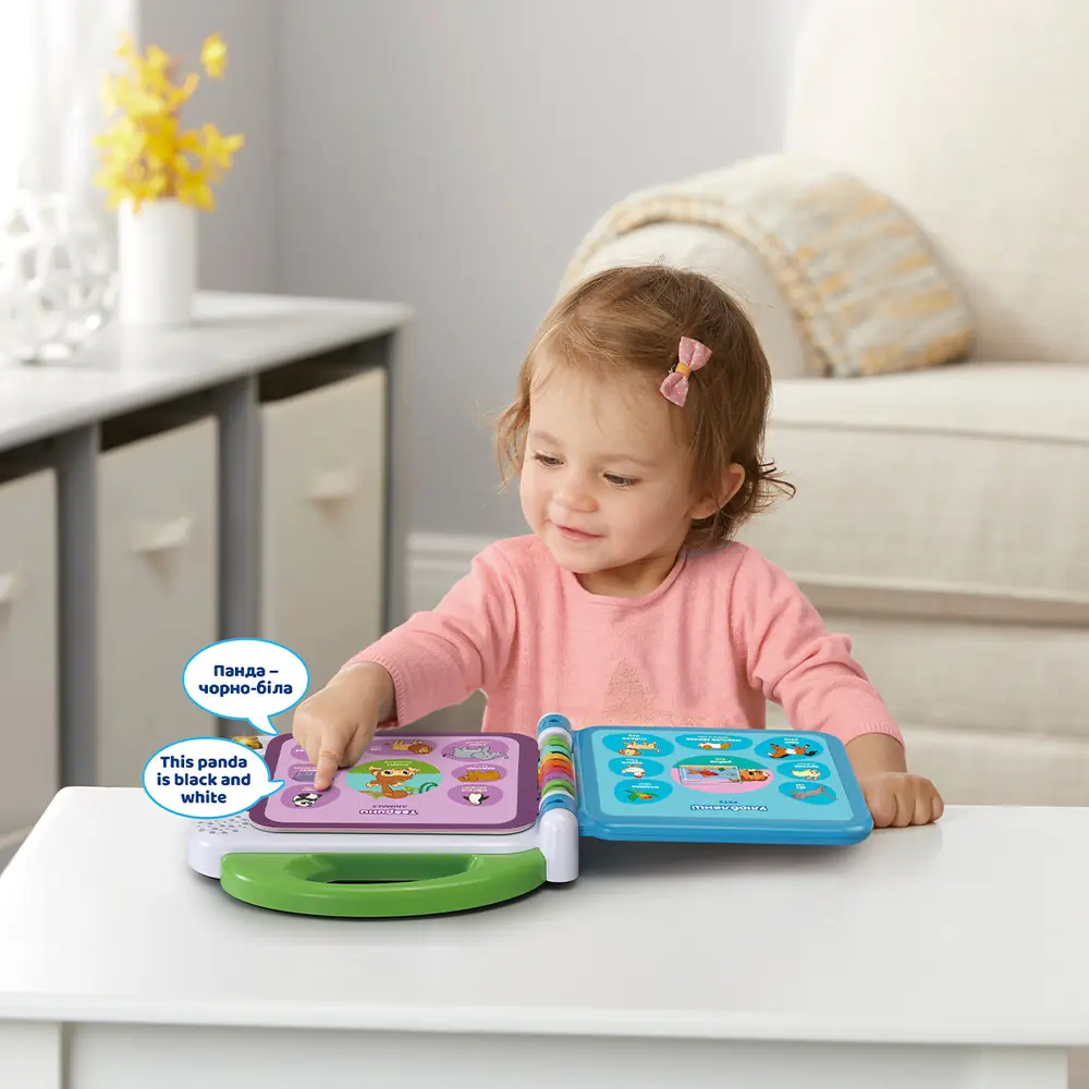 Дівчинка торкається сторінки розвивальної книги VTech